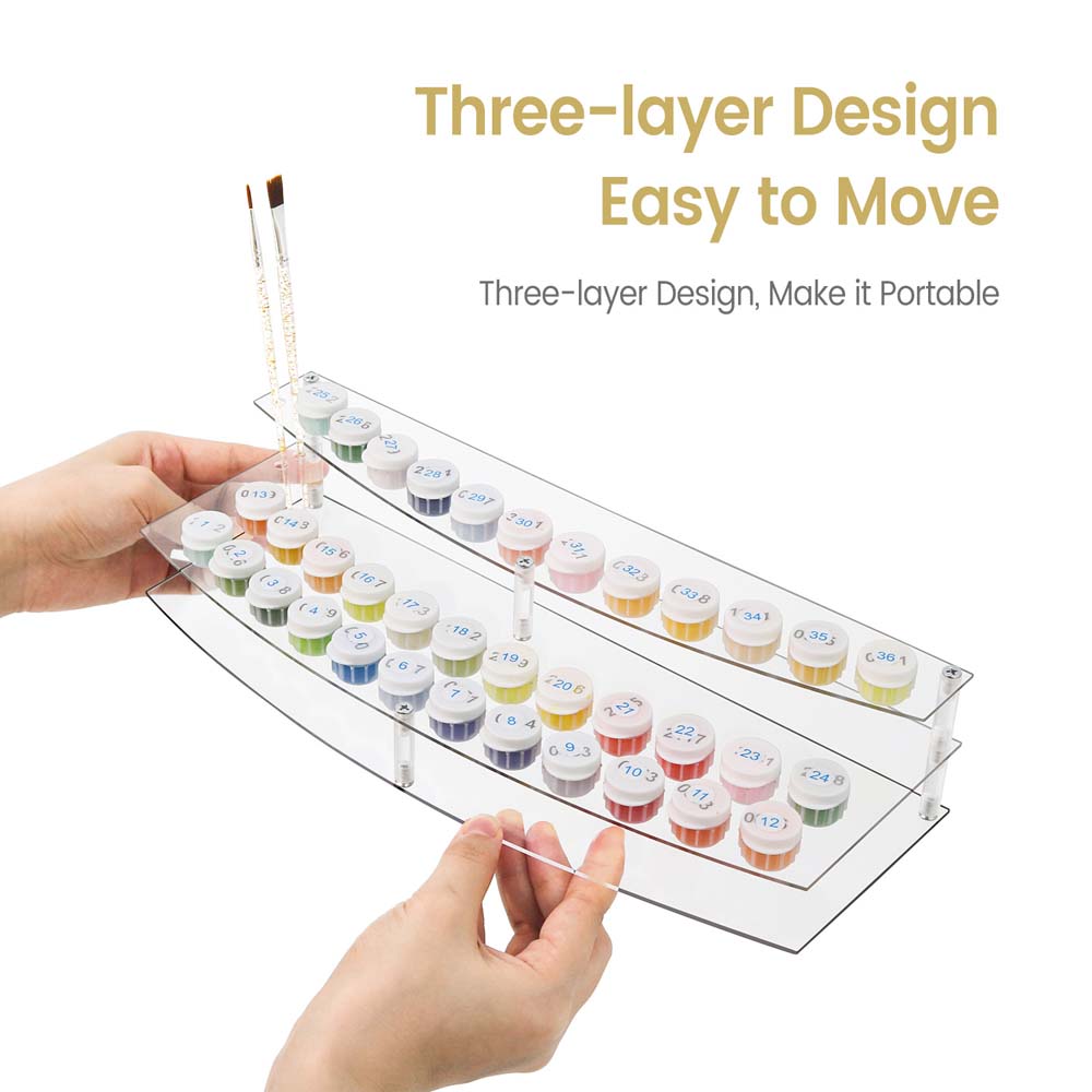 Clear acrylic tray with multiple small containers and a brush, held by hands against a white background.