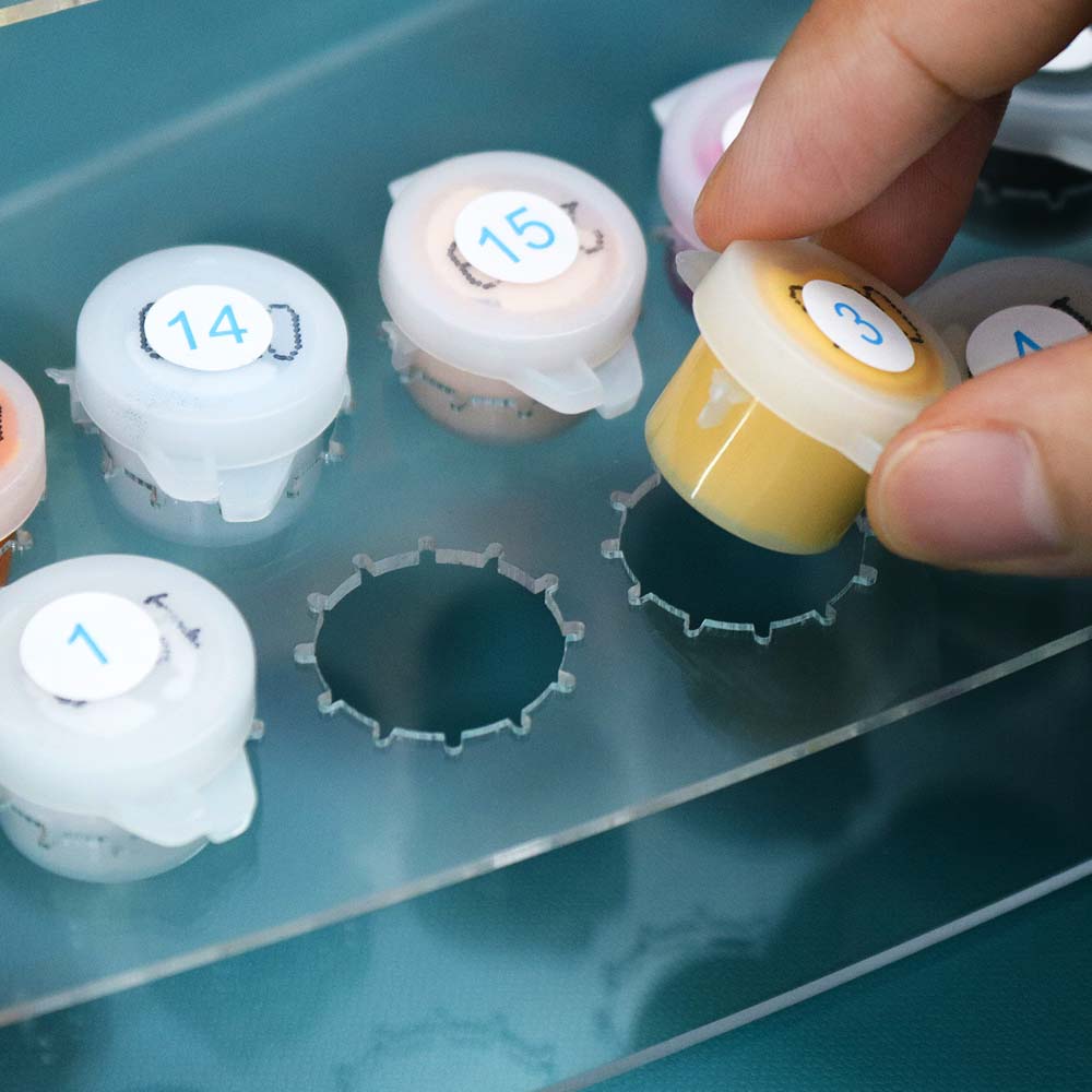 Hand selecting a labeled test tube from a rack with numbered containers.