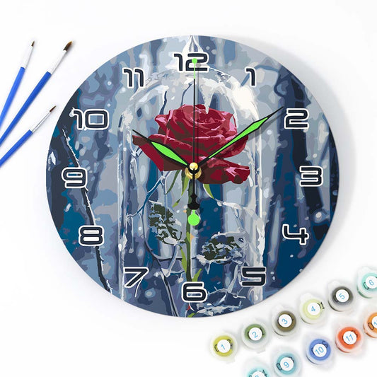 Wall clock with a rose design surrounded by painting supplies on a white background