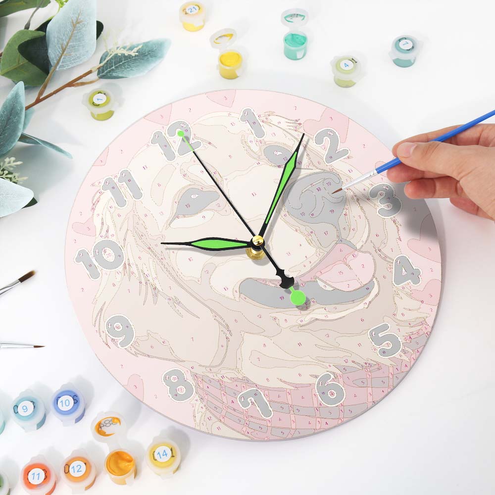 Person painting a decorative clock with a pink and gray design on a white surface.
