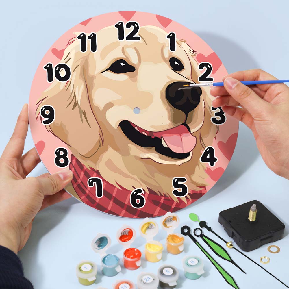 Painting a dog-themed clock with a hand holding a brush and paint supplies on a light blue background.