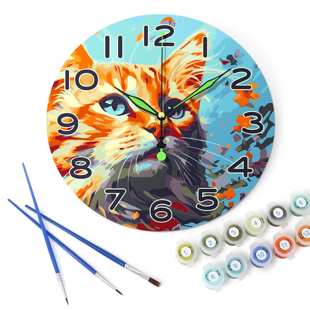 Decorative clock with a cat design, paintbrushes, and paint tubes on a white background
