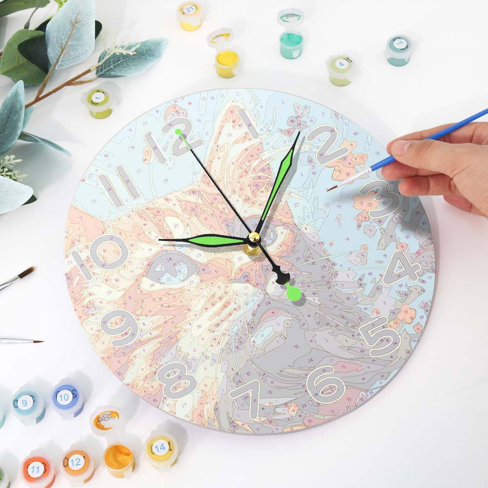 Decorative clock with artistic design on a white surface with paint supplies.