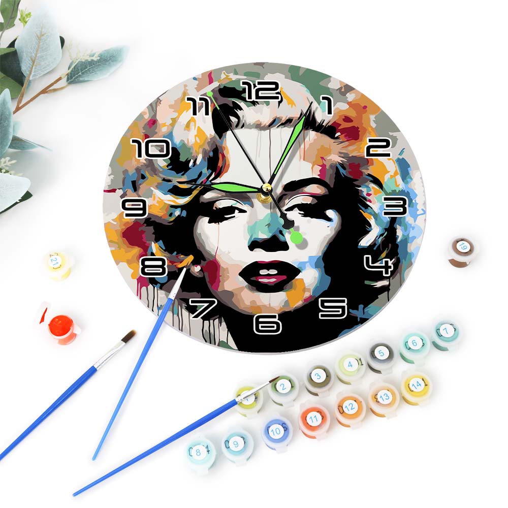 Decorative wall clock with artistic design of a face, surrounded by paint cans and brushes on a white background.