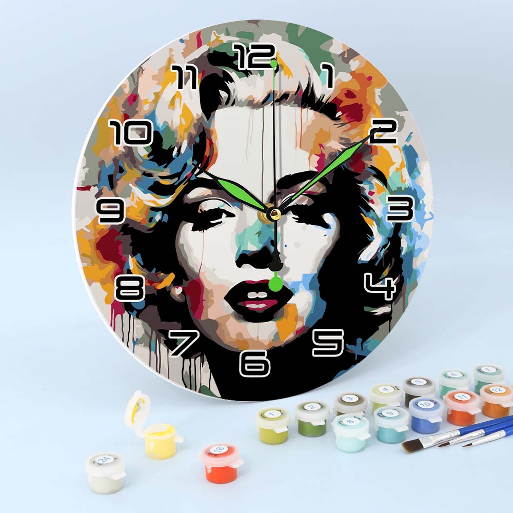Colorful wall clock with artistic design of a face, surrounded by paint cans and brushes on a light blue background.