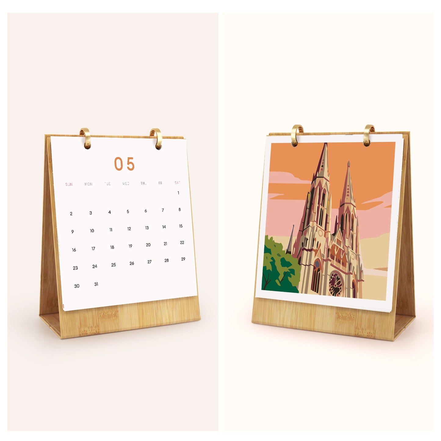 A desktop calendar stand shown in two views on a light warm background: one front view with a white page displaying the number 05 and a calendar grid, and one side view showing a printed illustration of a cathedral in warm orange, pink, beige, green, and brown tones. The stand has a light wood base and gold-toned rings.