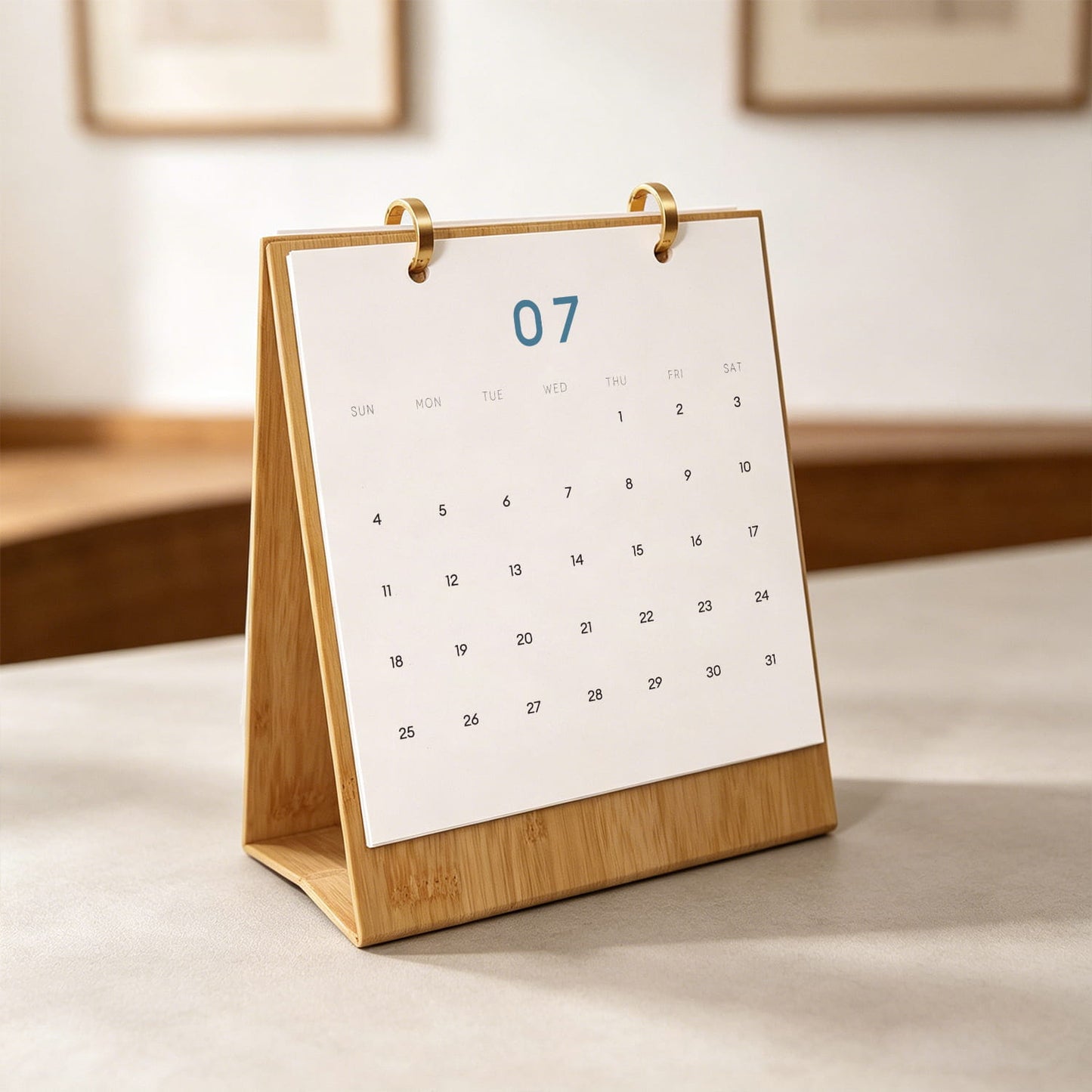 A bamboo desk calendar stand holding a white paper page with the date 07 highlighted in blue, photographed on a tabletop in a softly blurred indoor setting.