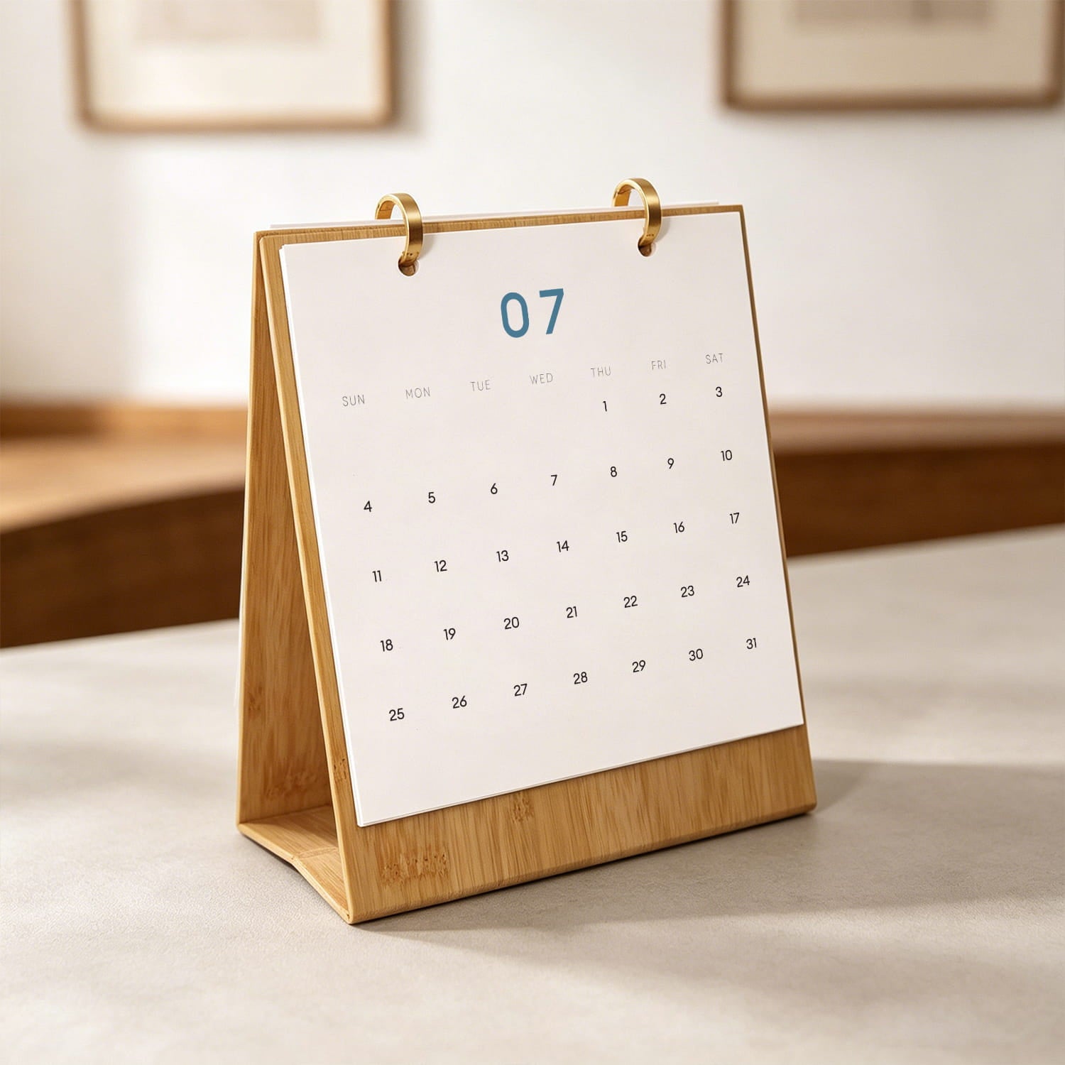 A bamboo desk calendar stand holding a white paper page with the date 07 highlighted in blue, photographed on a tabletop in a softly blurred indoor setting.