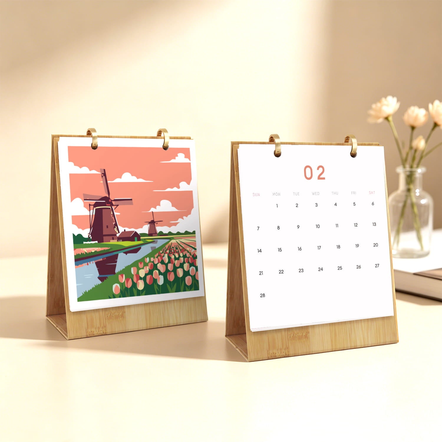 Two bamboo desktop calendar stands on a light beige surface. The left stand shows a colorful illustration of Dutch windmills and tulip fields, while the right stand shows a blank white calendar page with the date 02.