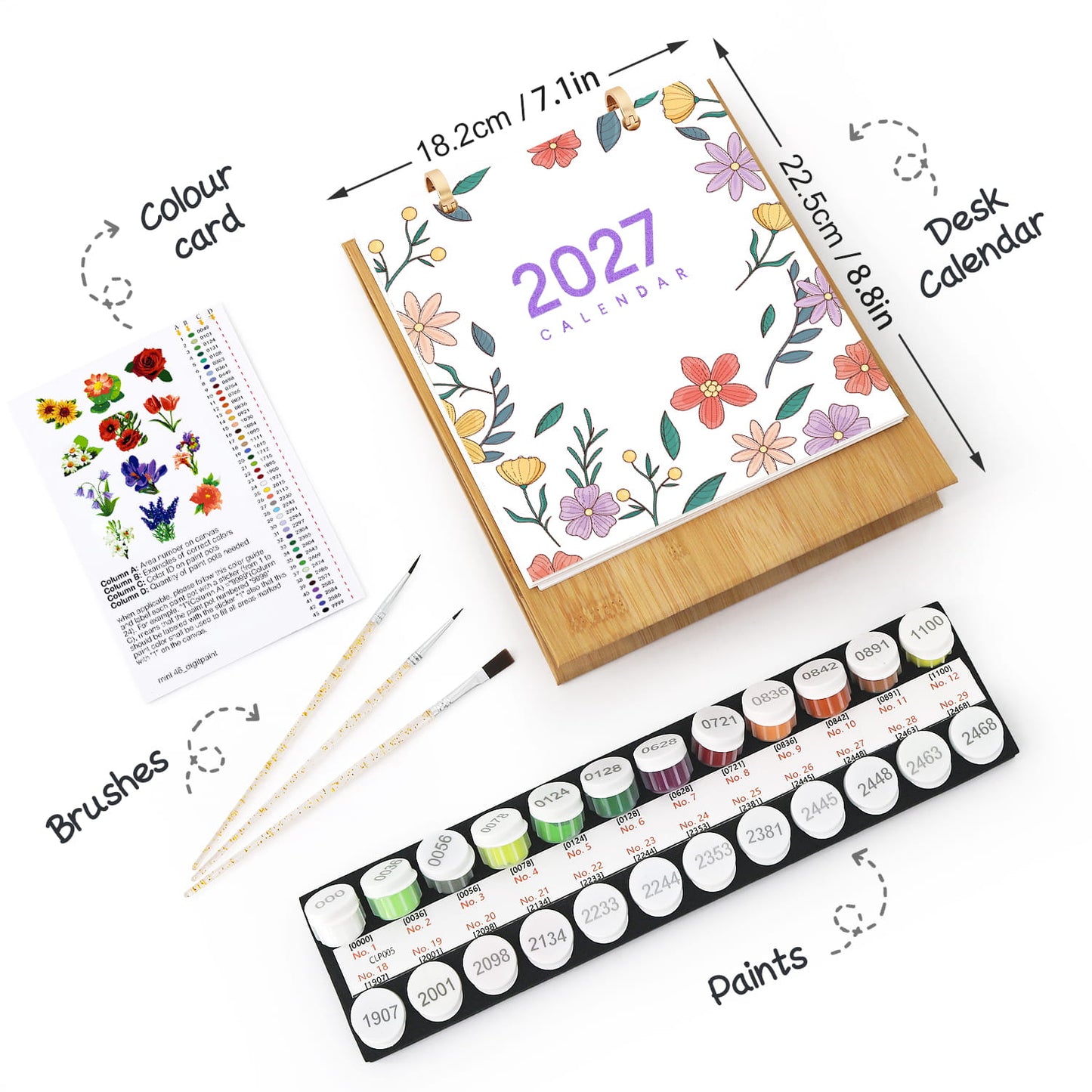 A flat-lay product presentation of a 2027 desk calendar kit, including the wooden-bound calendar with a floral cover, a color card, three paintbrushes, and a set of 24 watercolor paints in a black tray. The image features black text labels with arrows pointing to each component on a clean white background.