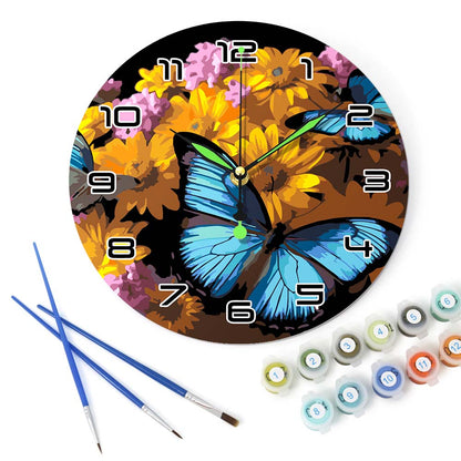 Decorative clock with butterfly and floral design, accompanied by paintbrushes and paint tubes.