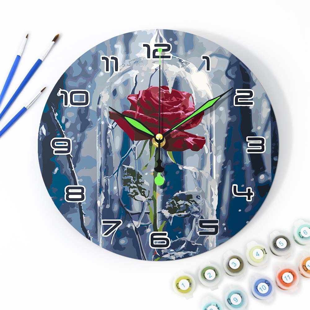 
Wall clock with a rose design surrounded by painting supplies on a white background
