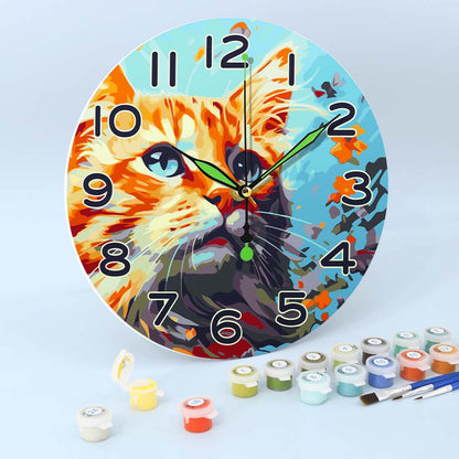 Wall clock with a cat design on a light blue background, surrounded by paint cans and brushes.