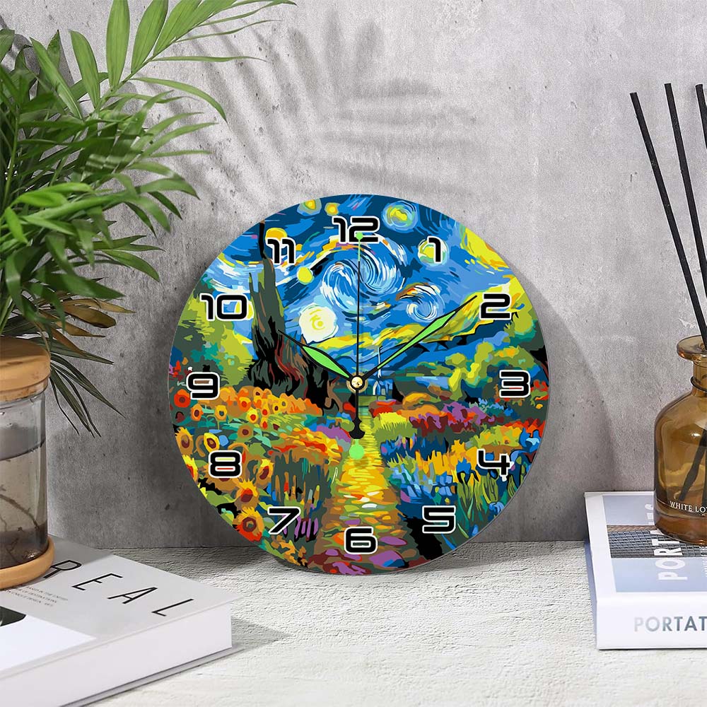 
Colorful wall clock with artistic design on a gray surface with a plant and books.